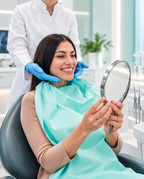Paciente sonriendo frente a un espejo en el sillón dental